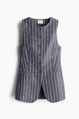 Chaleco largo de traje con cuello redondo y botones al frente. Diseño entallado con costuras moldeadoras en la cintura, bolsillos delanteros ribeteados y abertura en la parte posterior. Forrado y con estampado a rayas verticales blancas sobre fondo azul.