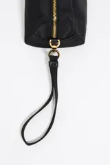 Neceser negro de nylon con estructura blanda y tamaño mediano. Tiene asa extraíble, detalles de piel, logo metálico de Bimba y Lola, acabados metálicos plateados, bolsillo interior y cierre con cremallera.