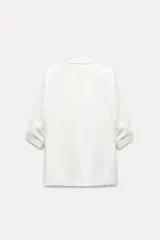 Blazer blanco con cuello solapa y hombreras. Manga por debajo del codo acabada en vuelta con trabilla y botón dorado. Bolsillos delanteros con solapa.