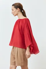 Blusa roja con escote bardot y mangas largas amplias.