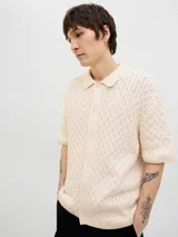 Polo de hombre color crema, tejido de punto cable, con cuello tipo polo, manga corta y cierre con botones.