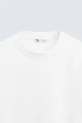 Camiseta blanca de algodón interlock con elasticidad, corte recto, cuello redondo y mangas cortas.