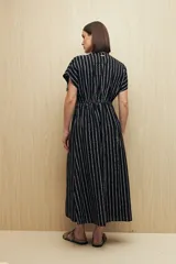 Vestido largo negro con estampado de líneas verticales blancas, escote en V, mangas cortas con lazo ajustable y corte fluido.
