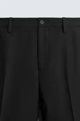 Pantalón de vestir azul marino, de corte slim fit, con bolsillos laterales y traseros. Se ajusta a la cintura con cinturón de cuero marrón.