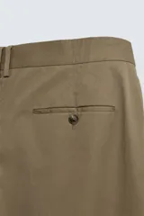 Pantalón color caqui de corte tapered relaxed fit, confeccionado en tejido de algodón. Presenta cintura con pliegues frontales dobles, bolsillos laterales en cadera y bolsillos traseros de vivo con botón. Cierre frontal con cremallera y botón.