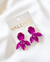 Aros colgantes con forma de flor, con piedras facetadas color fucsia engarzadas en metal plateado.