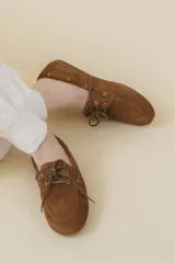 Mocasines náuticos de cuero color marrón, con cordones de cuero y suela de goma.