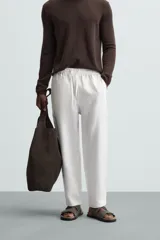Pantalón negro de lino, corte recto y relaxed fit, con cintura elástica ajustable con cordón, bolsillos laterales y traseros.