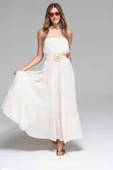 Vestido largo strapless color crudo, con volados escalonados y cinturón de soga con hebilla circular.