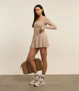 Short pollera deportivo color beige, confeccionado en microfibra ligera, con cintura ancha y calza interna.