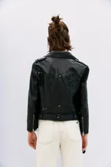 Campera negra de cuero ovino, estilo rocker, con cinturón, charreteras y solapas. Tiene cierres y detalles metálicos en frente y espalda.
