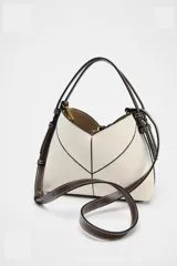 Bolso mini shopper de tejido canvas color crudo con pespuntes en contraste negro. Tiene asas de mano y correa bandolera extraíble. Incluye cartera interior con cremallera dorada.
