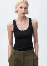 Musculosa negra de algodón con ribete blanco en cuello y sisas, corte ajustado y cuello redondo.