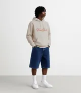 Hoodie color beige con capucha, cordones ajustables y bolsillo tipo canguro. Estampa bordada en el frente con la leyenda "Poona Studio".