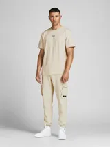 Camiseta de manga corta color beige, con cuello redondo y logo de la marca estampado en el pecho.