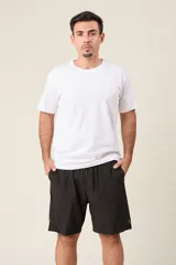 Bermuda deportiva de nylon color verde oliva, de corte suelto, con cintura elástica y cordón de ajuste. Cuenta con detalles de líneas verticales en los costados y bolsillos laterales con cierre.