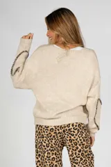 Saco largo color beige de tejido de punto con detalle de lazos con estampado animal print en el frente y en las mangas.