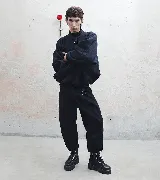 Pantalón sastre corte babucha color negro, con tablas, detalle de argolla metálica delantera y trasera, y tiro alto.