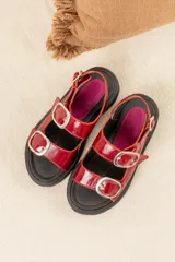 Sandalias rojas charoladas con hebillas plateadas, plataforma track negra y plantilla fucsia.