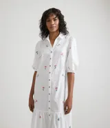 Vestido camisero midi blanco con estampado de flores rosas y celestes, manga corta abullonada, cuello camisero, abotonado al frente y falda con volantes.