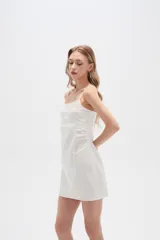 Vestido corto de algodón color negro, con breteles finos y detalle de broderie en la parte superior del pecho. Presenta un diseño entallado con cuello redondo y cierre.