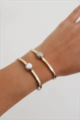 Pulsera rígida de bronce con piedra redonda de nácar engarzada.