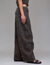 Pantalón de jean tiro alto con corte wide leg, confeccionado en denim gris oscuro con estampado de leopardo sutil. Presenta recortes verticales frontales y ruedo deshilachado.