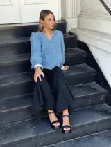 Camisa celeste de jean con cuello en V, mangas largas abullonadas con puños de encaje y cierre frontal con botones.