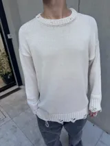 Sweater beige de hilo con cuello redondo y terminaciones rotas.