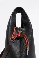 Bolso de mano negro marca Bimba y Lola, modelo Paper M, confeccionado en piel vacuna con estructura blanda. Incluye asa extraíble, bolsillo interior, etiqueta de tejido y logo metálico plateado.