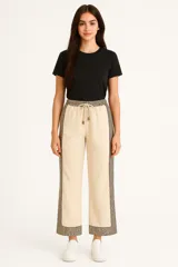 Pantalón de corte recto color beige con cintura elastizada y cordón ajustable. Presenta estampado animal print en los laterales y en el ruedo.