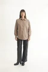 Camisa color beige de corte clásico con cuello, mangas largas y bolsillo frontal.