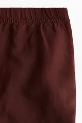 Pantalón tobillero marrón de corte holgado en tejido liviano de mezcla de lino. Modelo de tiro alto con elástico revestido y cordón para ajustar fino en la cintura, bolsillos al bies y piernas ajustadas.