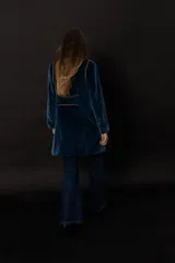 Chaqueta azul de terciopelo con corte levita, cuello mao y doble botonadura dorada.