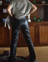 Pantalón de cuero negro, tiro alto, de corte recto y largo hasta el tobillo.