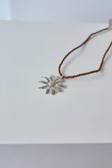 Collar con dije de acero quirúrgico hipoalergénico en forma de margarita plateada y tiento sailor color borgoña.