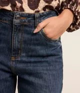 Pantalón de jean de corte recto con cintura alta, color azul oscuro, con bolsillos delanteros y traseros. Se ajusta a la cintura con cinturón de cuero marrón.