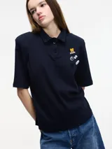 Remera tipo polo blanca de manga corta con hombreras y pins removibles en la delantera.