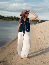 Chaleco de denim azul con bordado de margaritas blancas y logo de la marca en la parte superior.