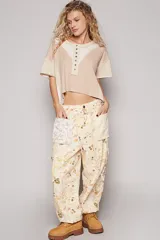Remera corta color beige con diseño patchwork, escote redondo con botones y mangas cortas.