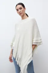 Capa tejida color negro, con cuello redondo, diseño de punto y detalles de lentejuelas. Presenta flecos en el dobladillo.