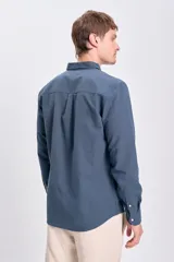 Camisa de lino azul oscuro de corte clásico, con cuello abotonado y bolsillo en el pecho.