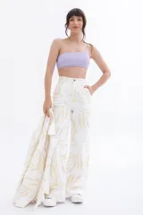 Pantalón jean blanco con estampado de hojas en tonos pastel.