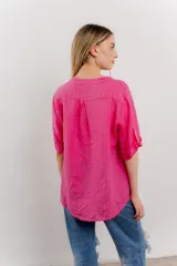Camisa azul de lino con escote en V abotonado, bolsillo frontal y mangas 3/4 con trabilla.