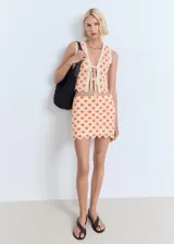 Falda corta de tejido crochet con diseño de flores en naranja y crema, bajo festoneado.