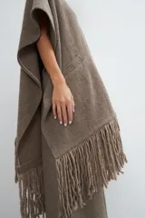 Ruana color crema de lana fina con flecos en el ruedo y bolsillos delanteros.