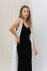 Chaleco largo tejido en punto calado color beige, de silueta recta y caída fluida. Presenta un diseño artesanal con transparencias sutiles que aportan textura y movimiento.