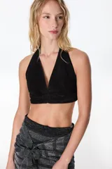 Top corto negro de cuero con escote halter y espalda descubierta.