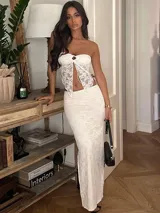 Conjunto de dos piezas blanco, compuesto por un top estilo bandeau de encaje con lazo central y una falda larga ajustada de encaje.