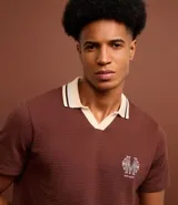 Camisa polo marrón con textura, cuello con detalle contrastante en beige y logo bordado en el pecho.